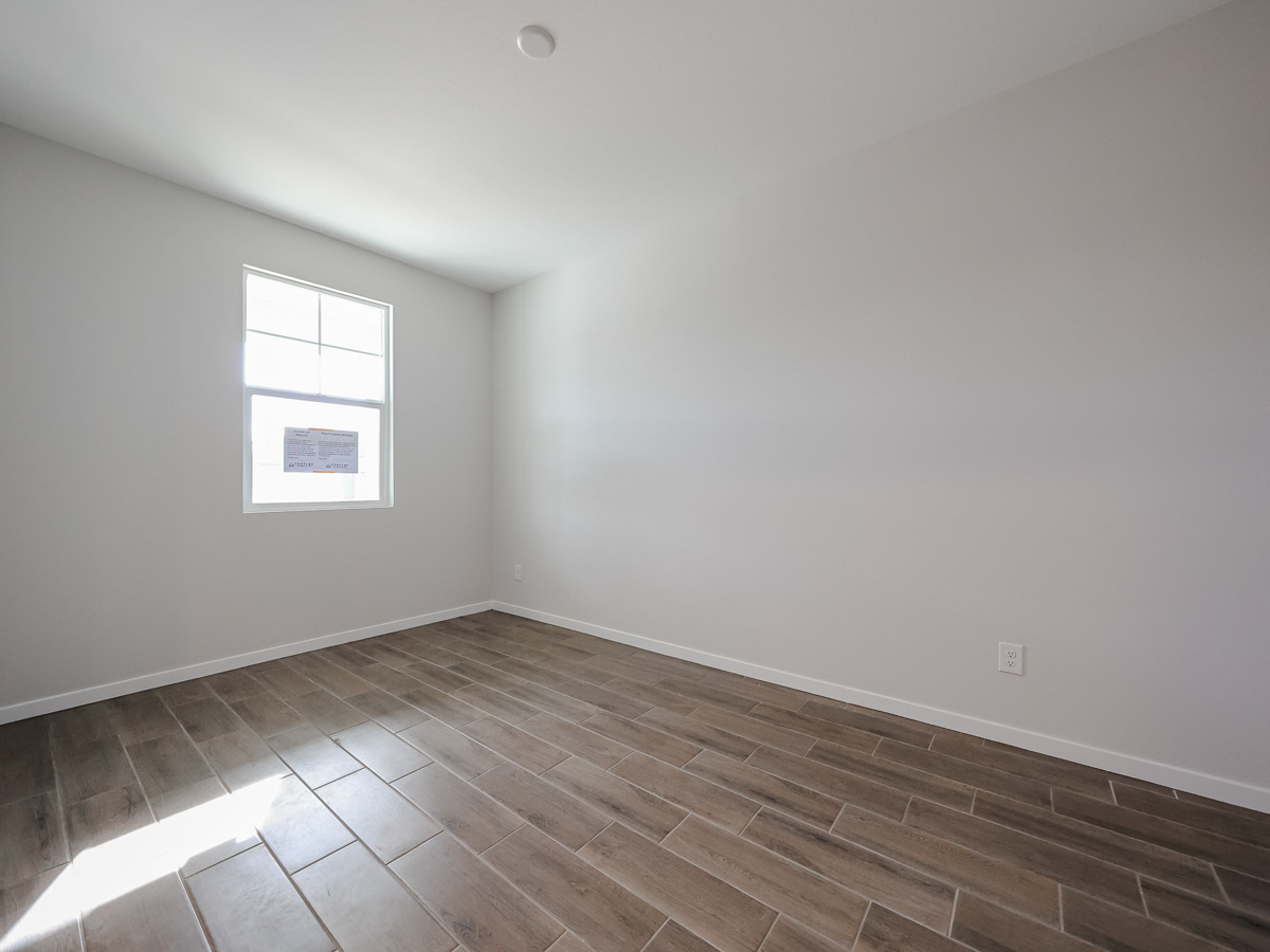 A room with a wood floor and a tile floor with a window.