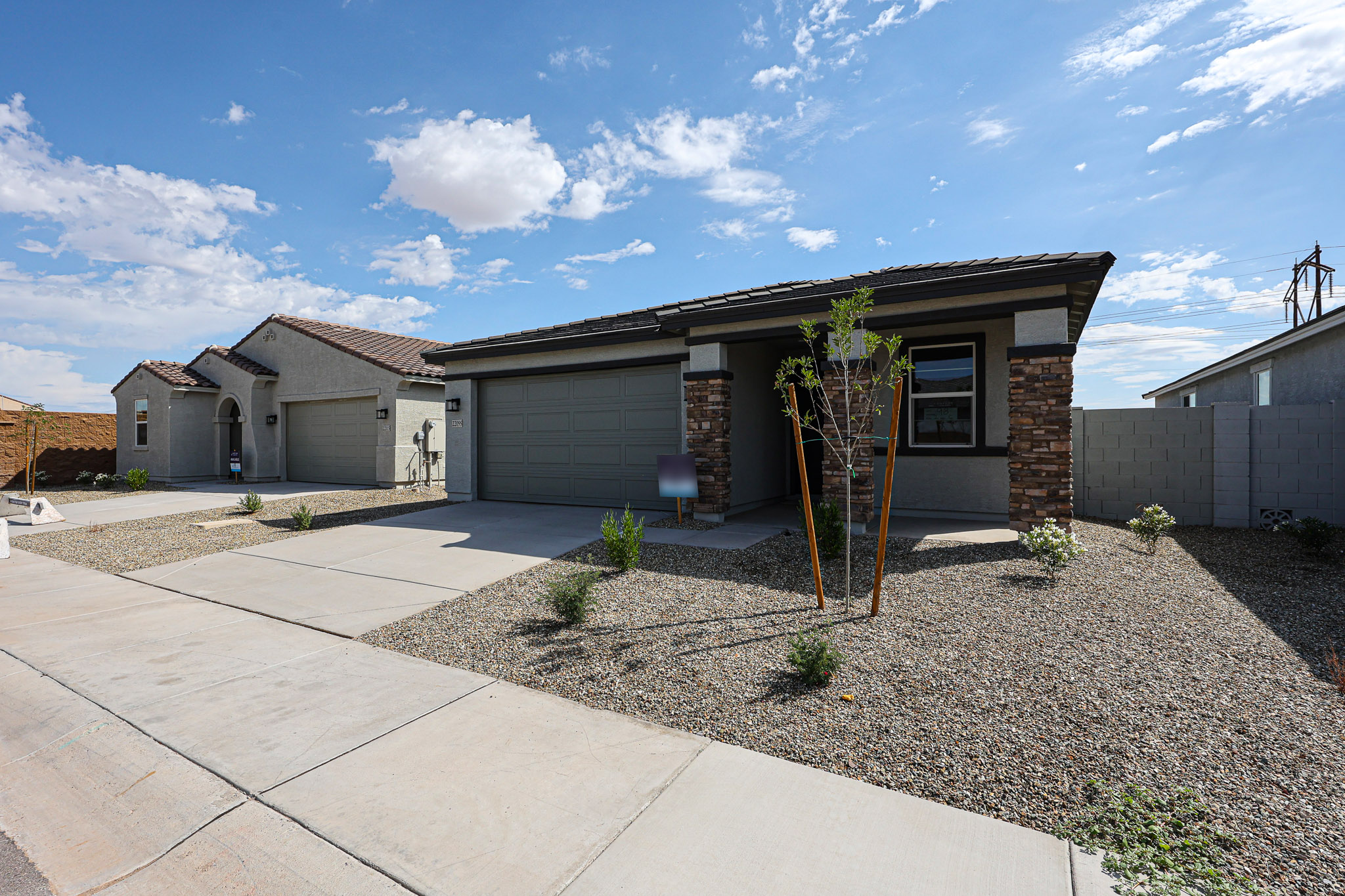 A driveway with a house and a tree in the front.