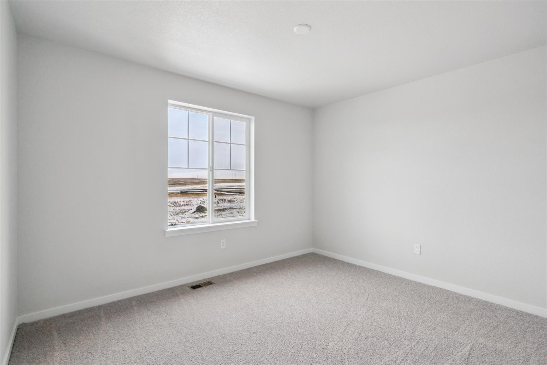 A room with a window and a white wall.