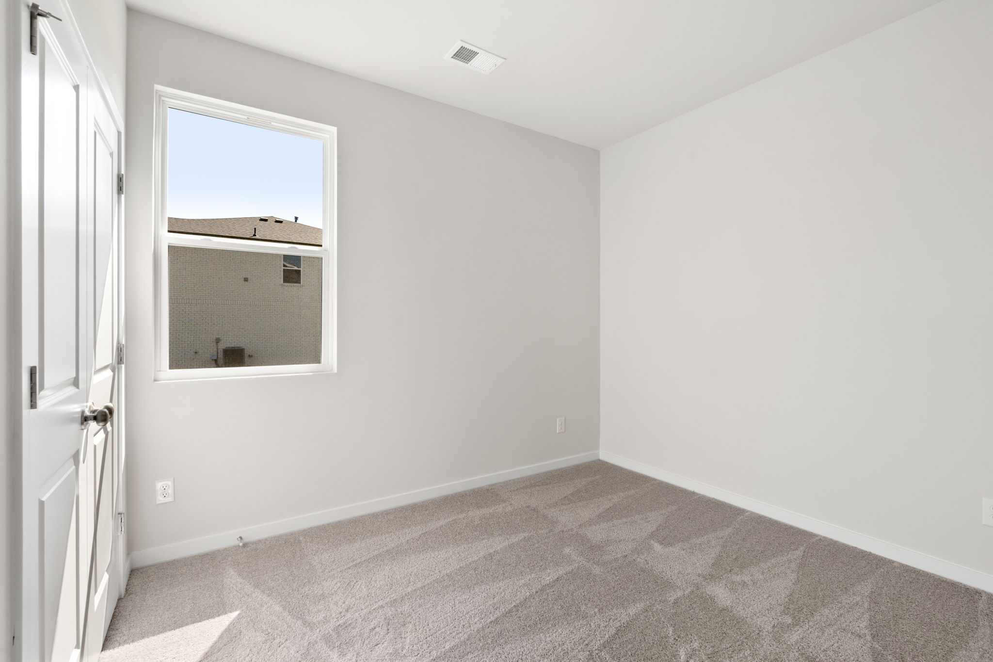 A room with a window and a rug.