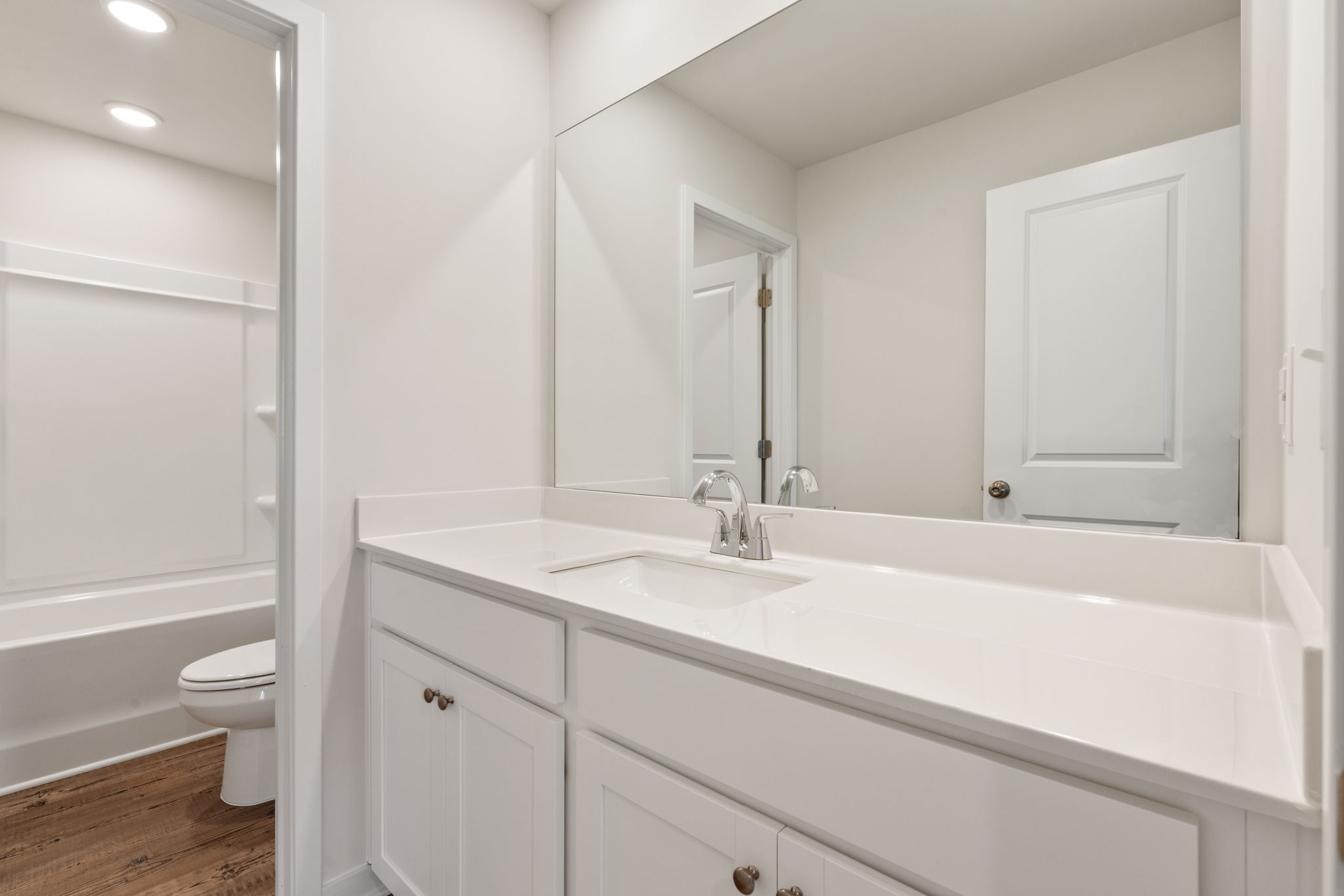 A bathroom with a sink toilet and mirror.