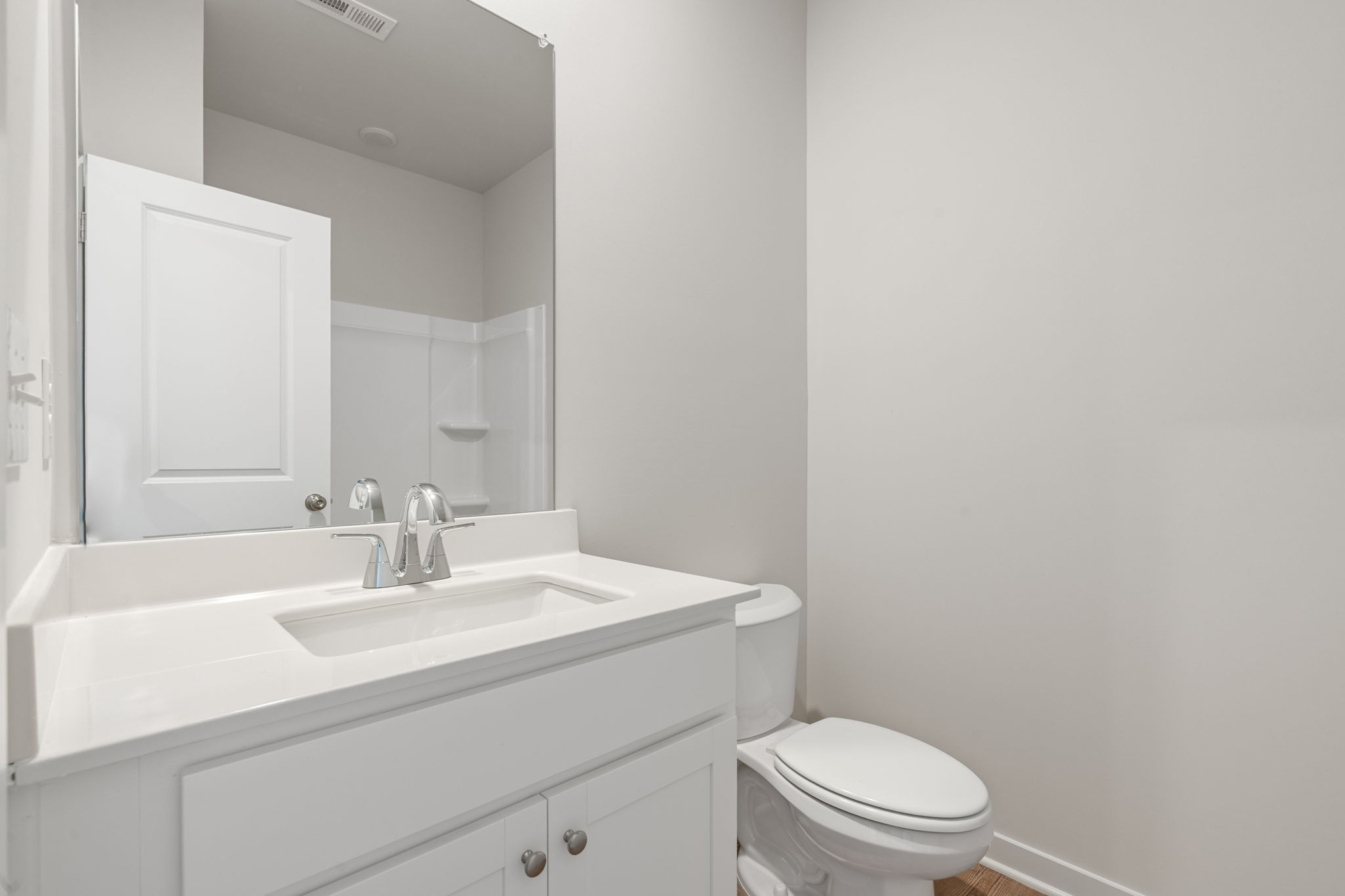 A bathroom with a sink toilet and mirror.