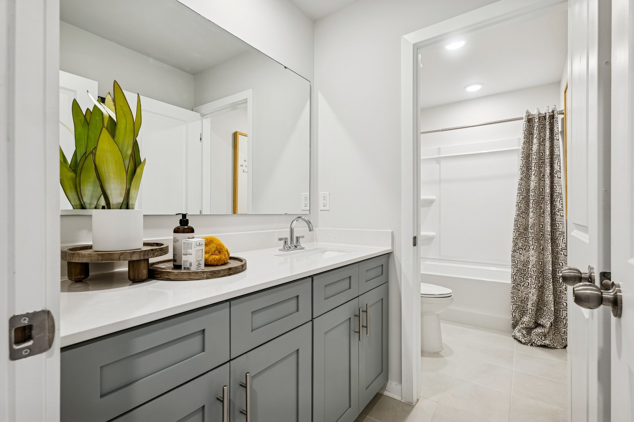 A bathroom with a sink toilet and mirror.
