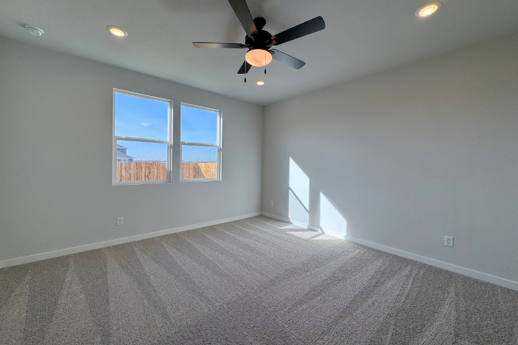 A room with a ceiling fan and a window with a light.