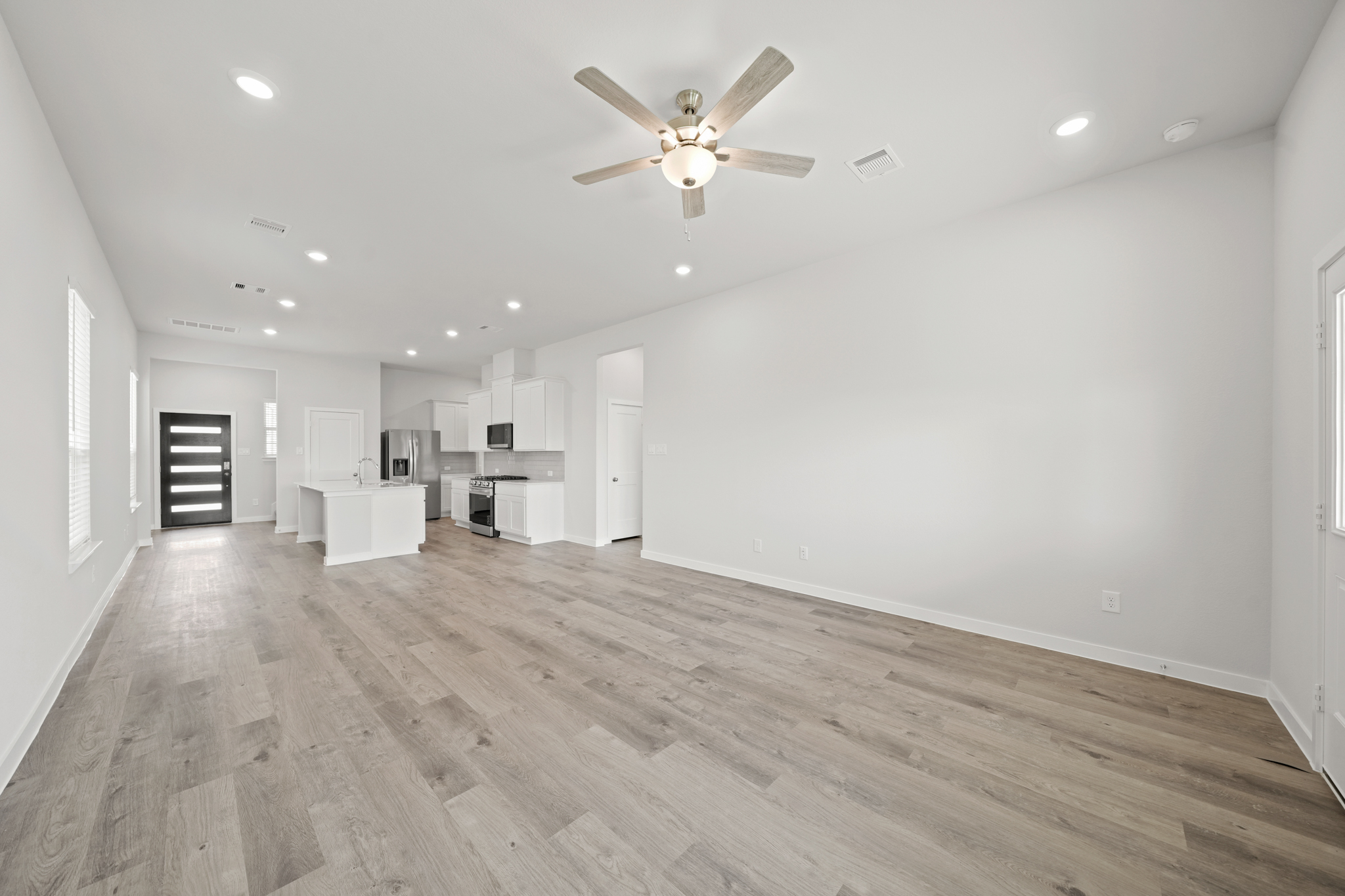 A large empty room with a ceiling fan and a wood floor.