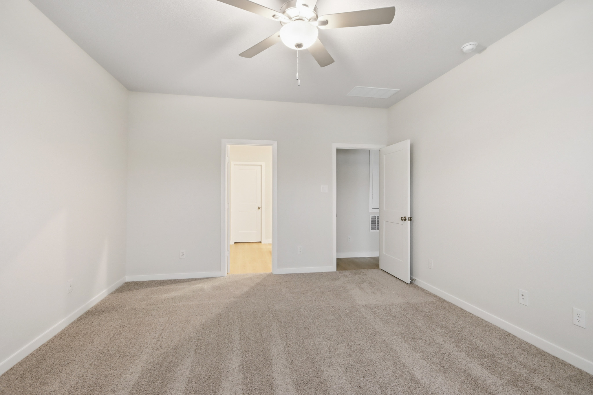 A room with a ceiling fan and a door.