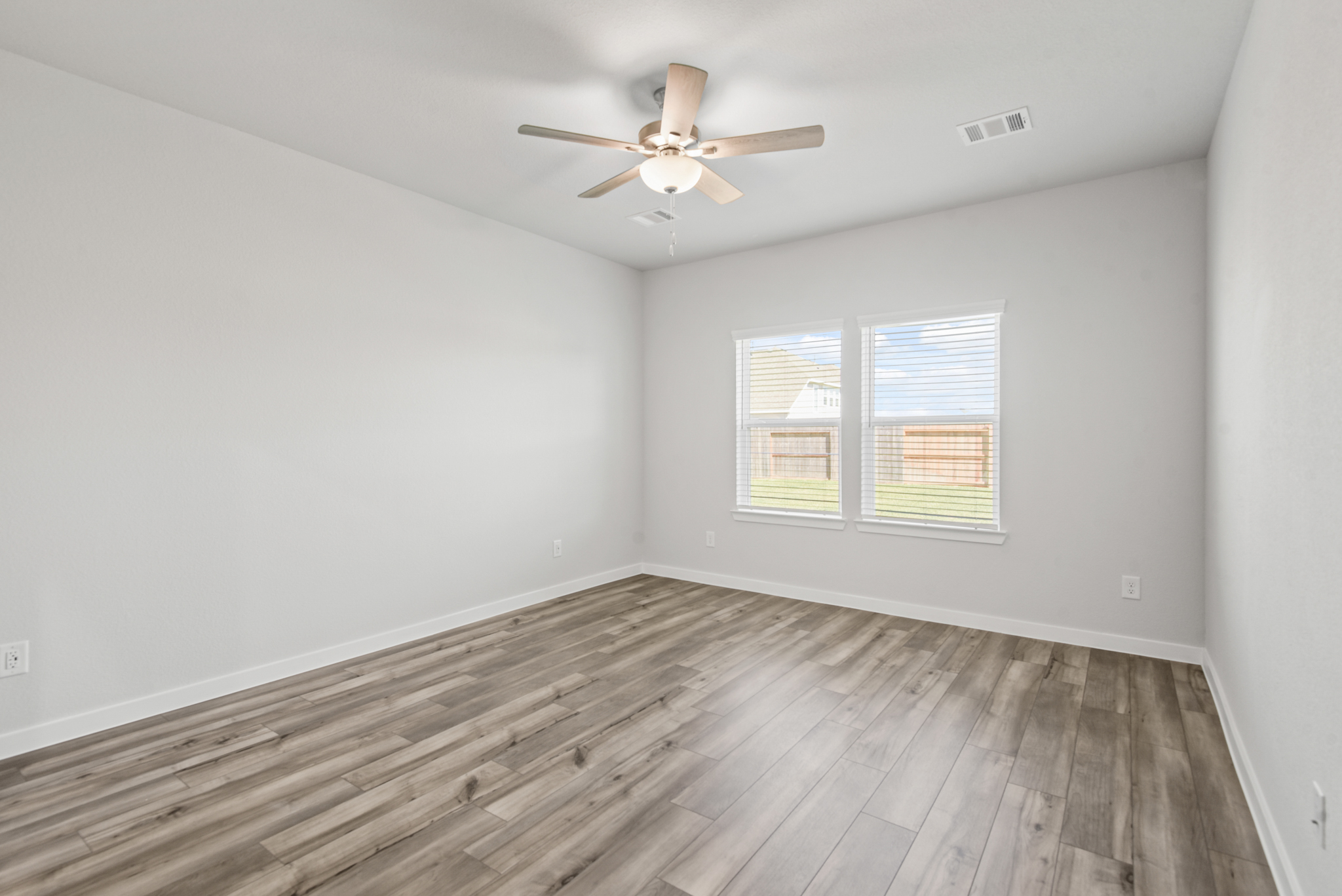 A room with a ceiling fan and wood floor.