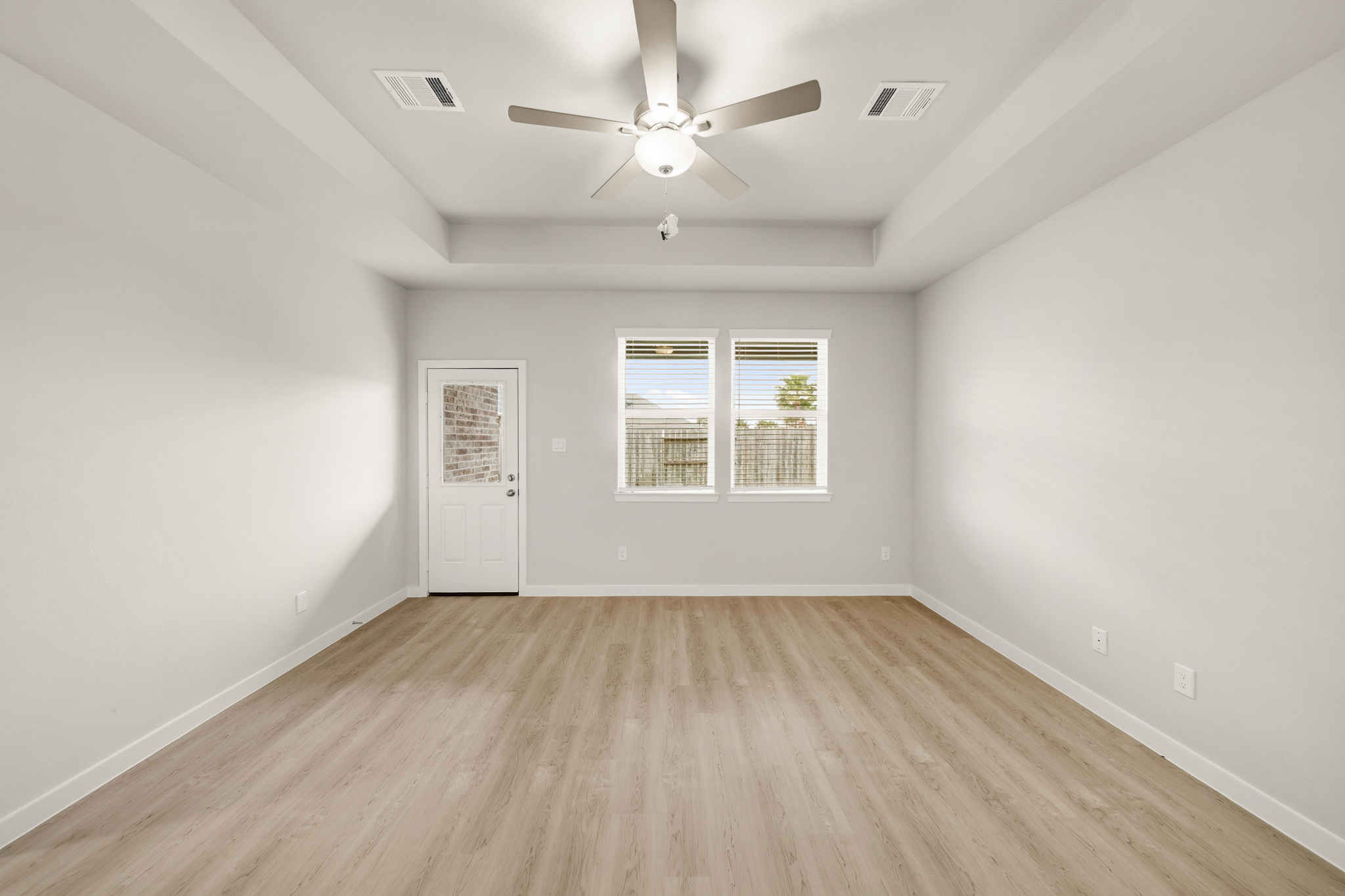 A room with a ceiling fan and a wood floor.