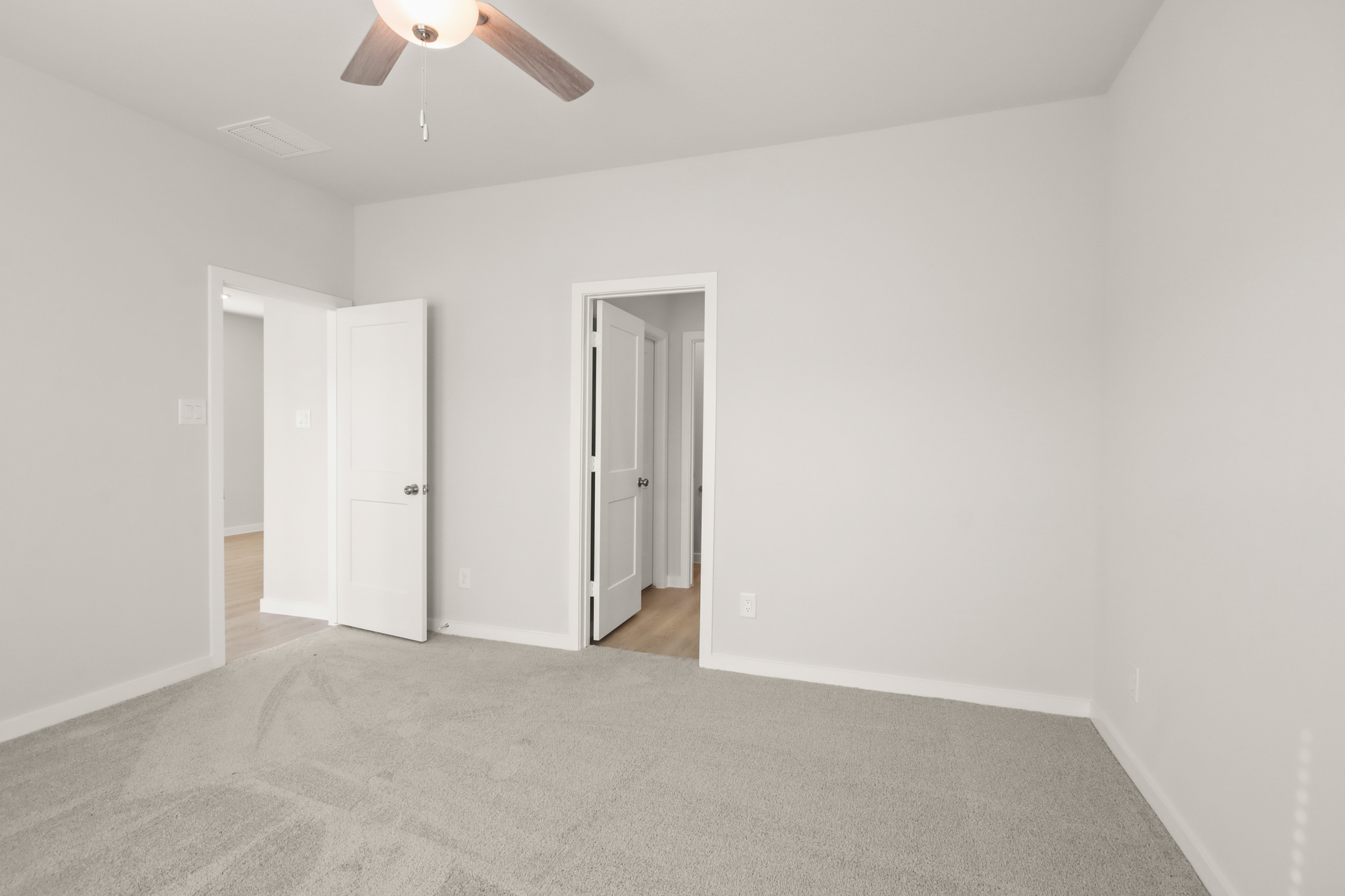 A room with white walls and a ceiling fan.
