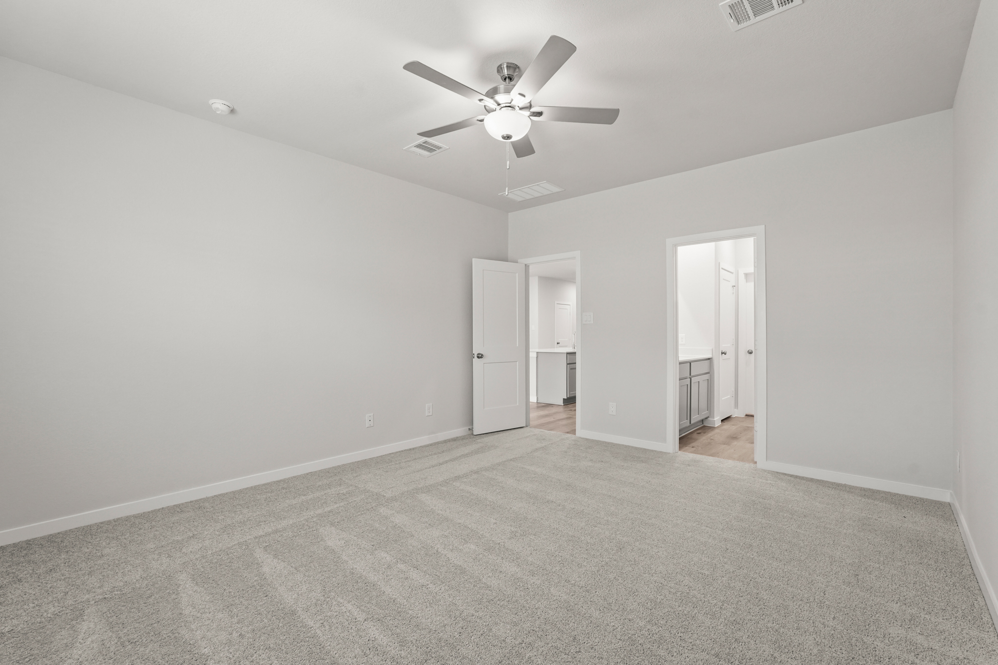 A room with a ceiling fan and white walls.