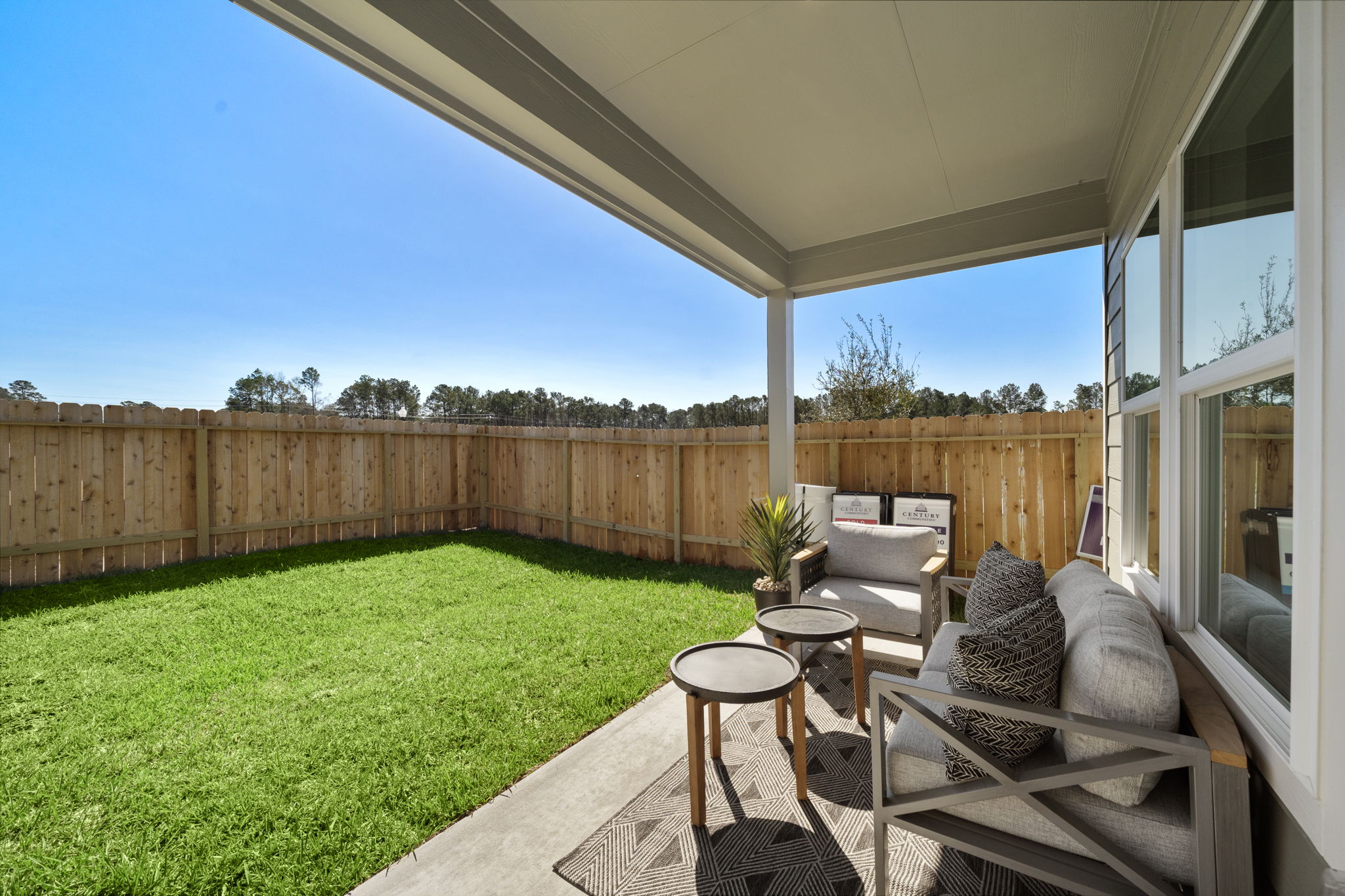 A backyard with a fence and a patio with a table and chairs.