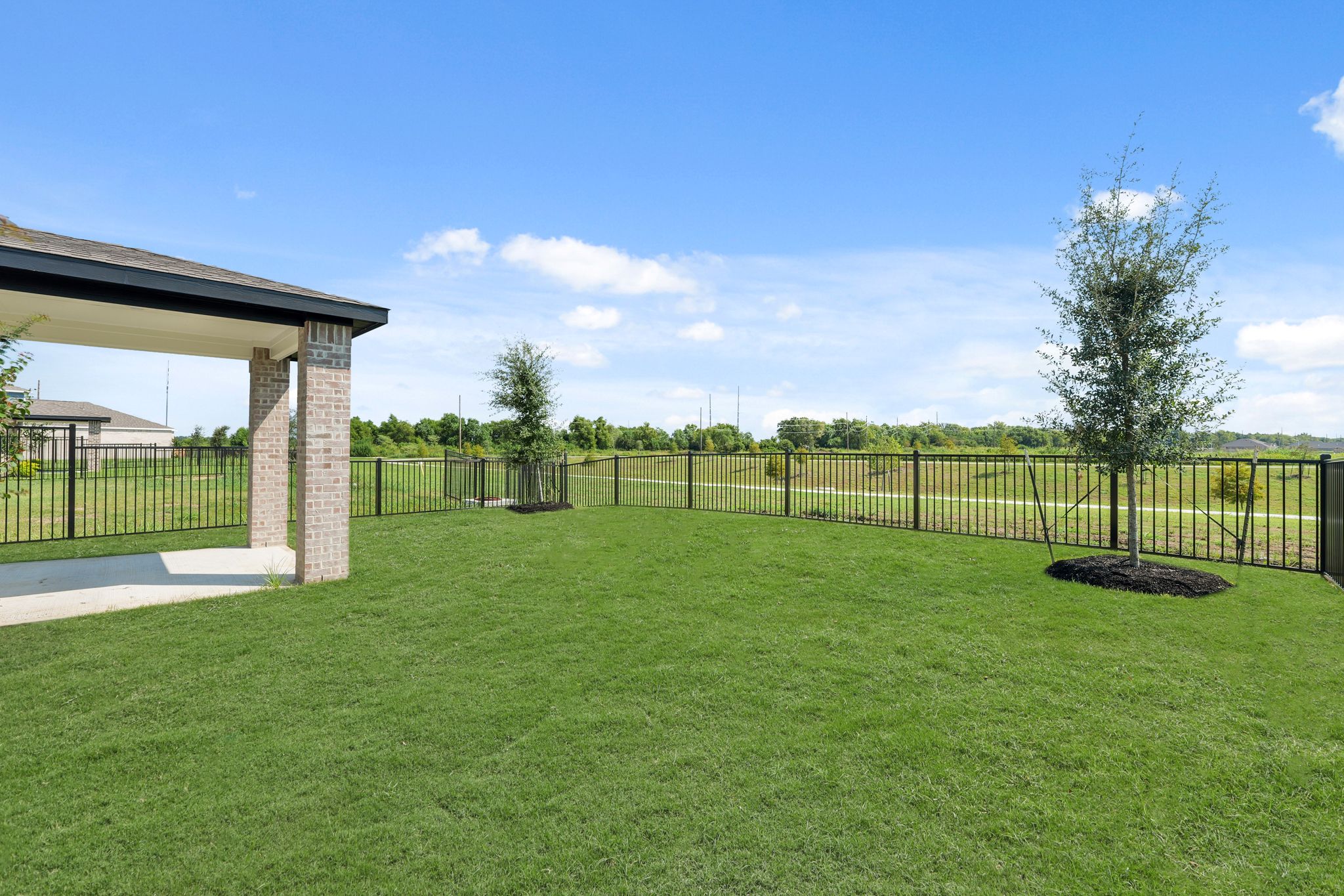 A large green lawn with a fence and a tree.