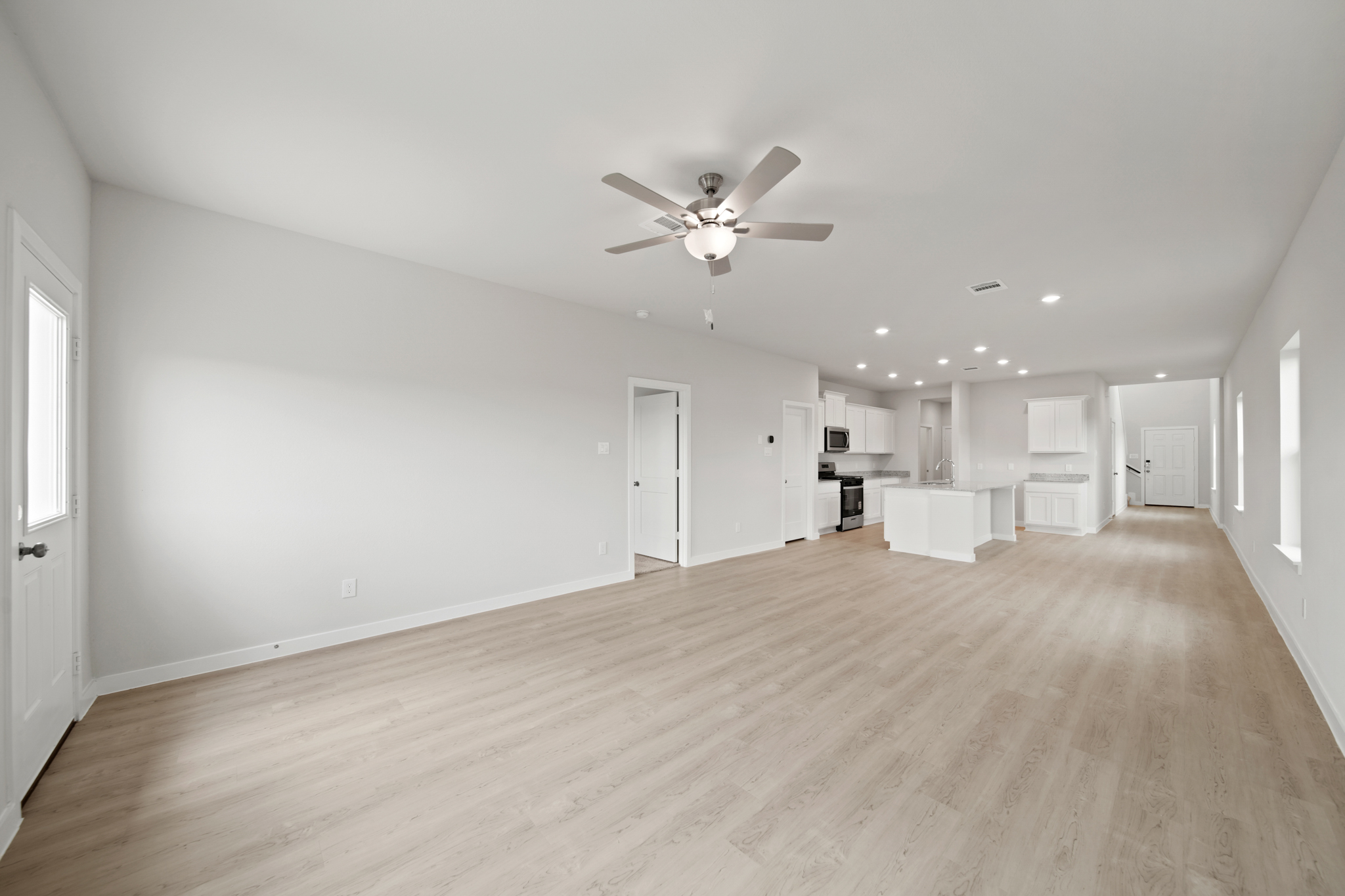 A large empty room with a ceiling fan and a wood floor.