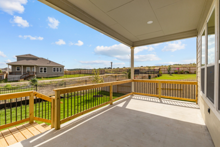 A deck with a railing and a building in the background.