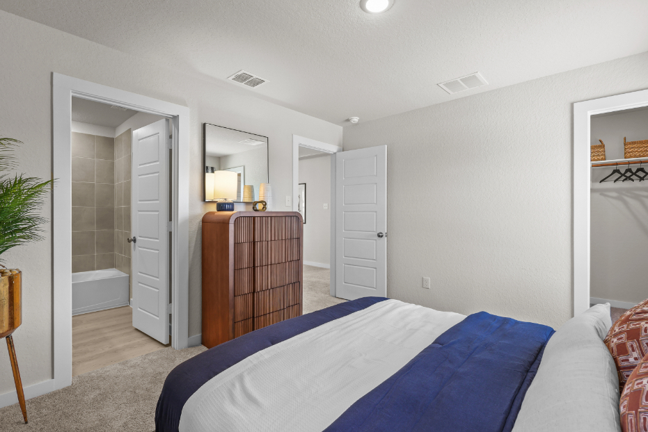 A bedroom with a bed and a mirror.