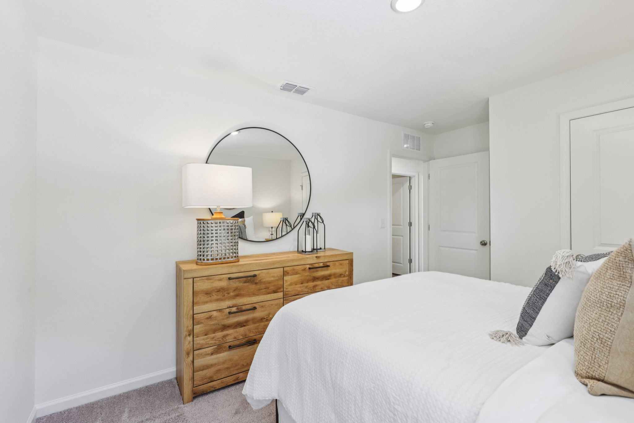 A bedroom with a mirror and a bed.