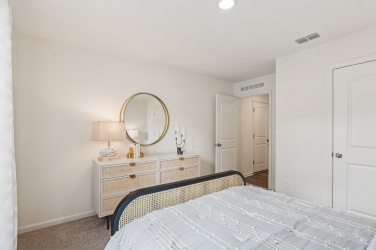 A bedroom with a mirror and a bed.