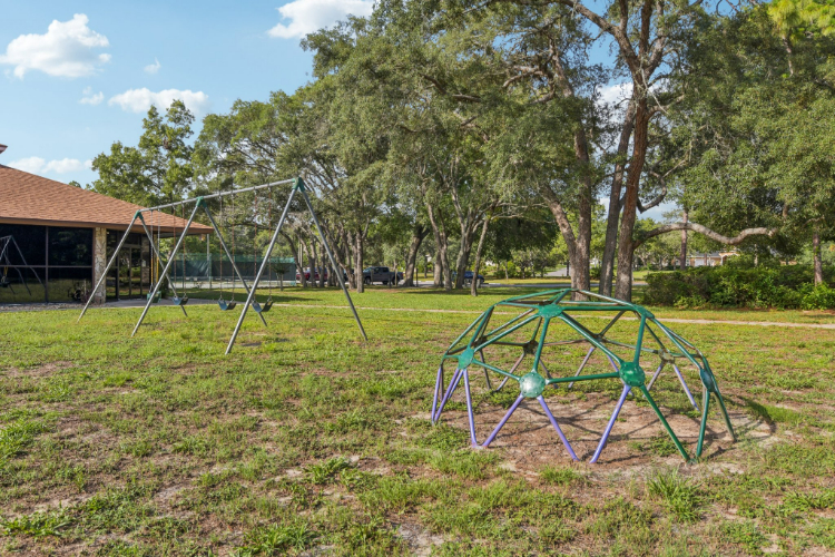 A blue trampoline in a yard with trees and a building.