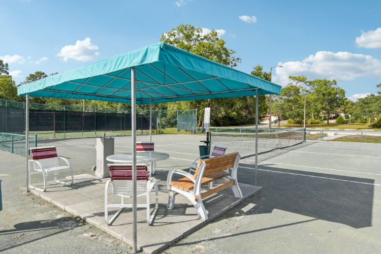 A table and chairs under a green awning.