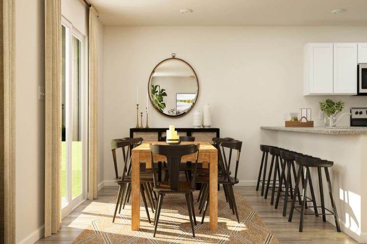 A dining room with a round mirror.